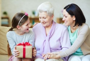 Young and elderly women looking at gift-box held by teenage girl