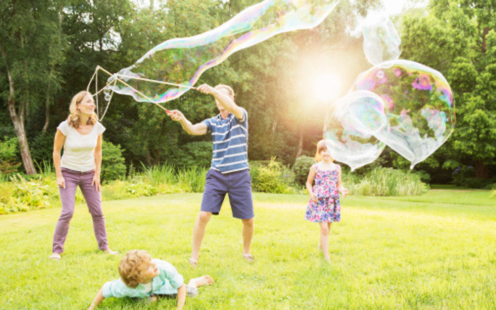 Family playing with large bubbles in backyard